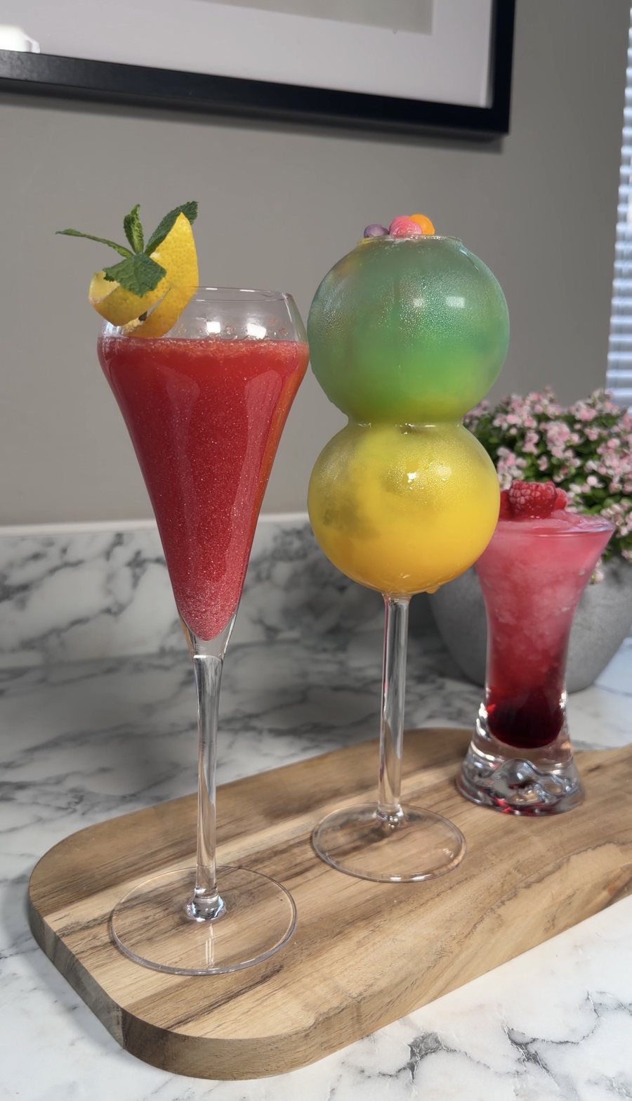 Three colourful mocktails on a wooden serving board