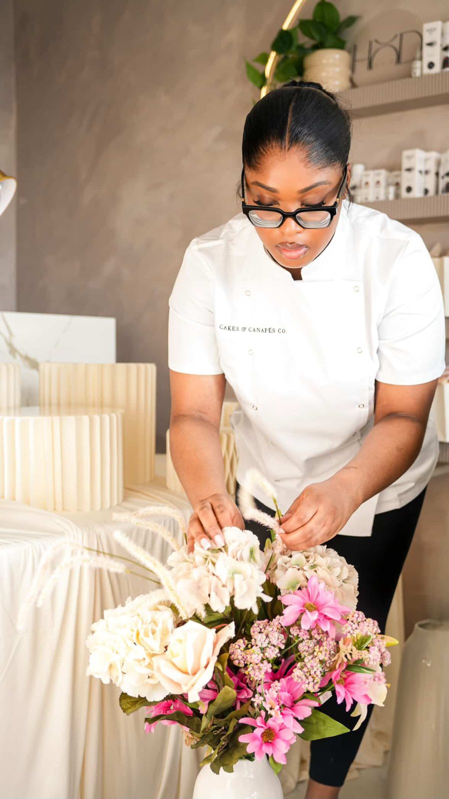 Omozele arranging flowers in her Cakes & Canapés Co. chef jacket